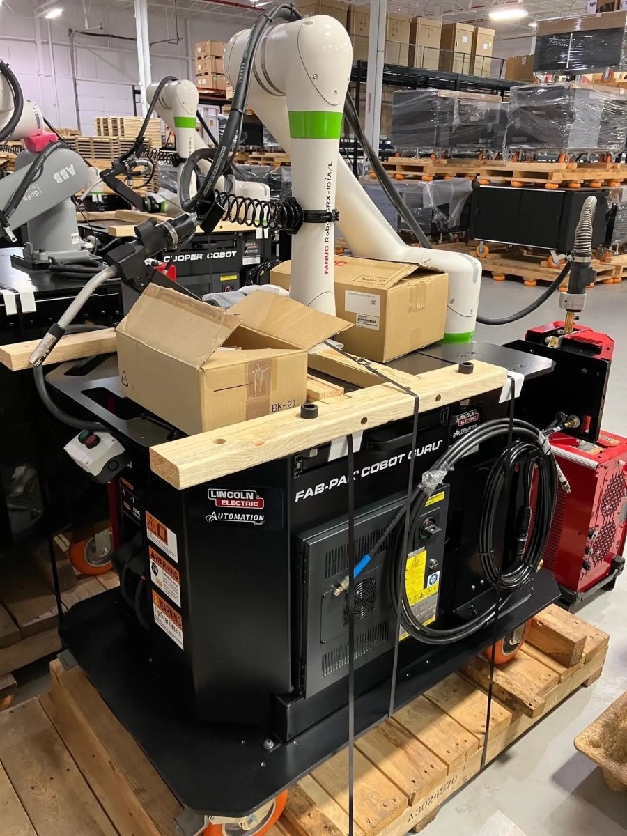 Lincoln Cooper CRX-10iA/L Air-Cooled Welding Cobot Cart (AD2489-8) in warehouse with gear, pallets, boxes & cables.