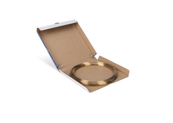 A thin coil of Harris 45T350 Safety-Silv 45T silver brazing alloy, 1/16 in (1.6 mm), is neatly arranged inside a partially open flat box (50 toz), revealing the organized circular coil against a white background.
