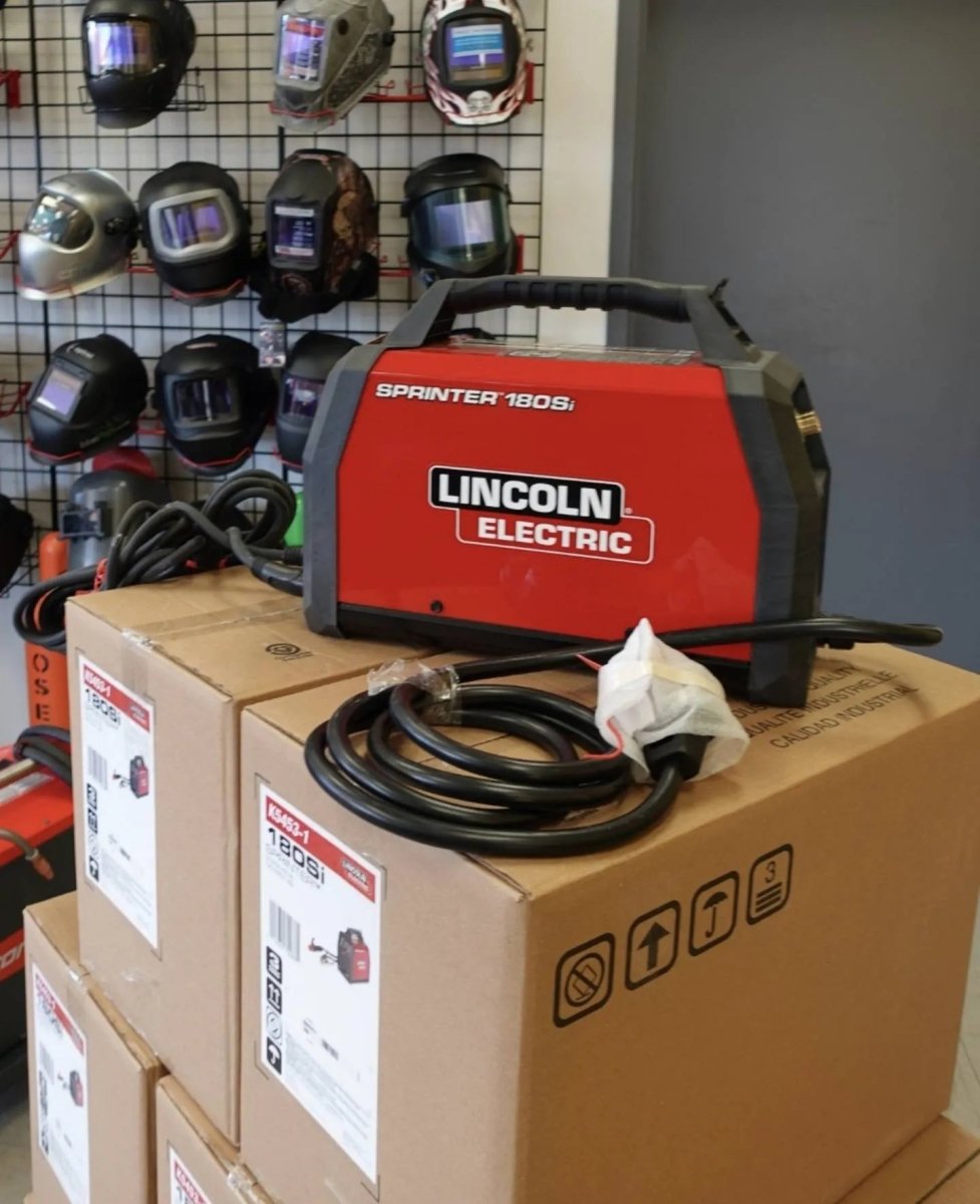 Lincoln Sprinter 180Si Factory Demo Welder U5453-1 on boxes, with welding helmets and cables at WeldingMart welding equipment store.