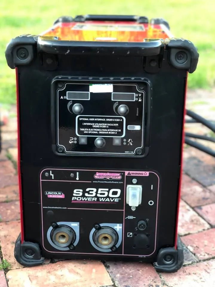 A Lincoln Electric Power Wave S350 Advanced Process Factory Demo Welder (U2823-3) sits outdoors on a brick surface, clearly showing its control panel, connectors, and labels.