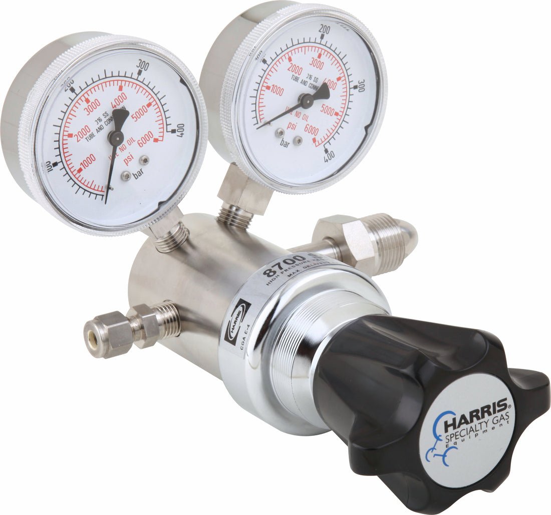 The Harris 8700SS SR-6000-677 - 3200407 Argon/Helium/Nitrogen Regulator is a stainless steel single stage pressure regulator with two pressure gauges, threaded connectors, and a black adjustment knob labeled Harris Specialty Gas.