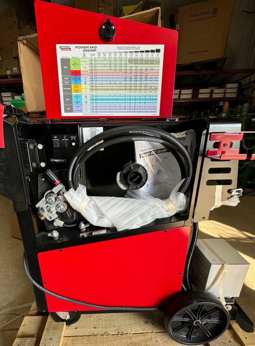 Lincoln Power MIG 262MP Multi-Process Welder on wheels in workshop, open panel showing welding components, wires, and chart.