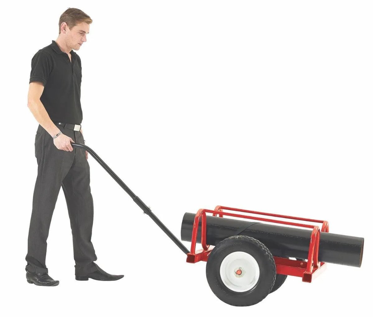 A man in a black shirt and gray pants pushes a Mathey Dearman Baby Buggy 20 Pipe Transport (2013), carrying a large black cylinder. This cart has white-rimmed wheels, a metal handle, and holds up to 1,000 lbs, set on a plain white background.