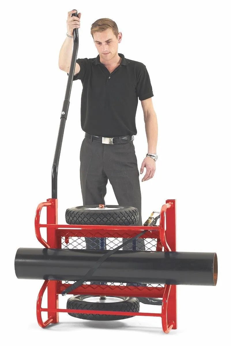 A man in a black polo and gray pants operates the Mathey Dearman B&B Baby Buggy 20 Pipe Transport (2013), a red cart with metal mesh frame and large tires, moving a black pipe. Capacity: 1,000 lbs. White background.