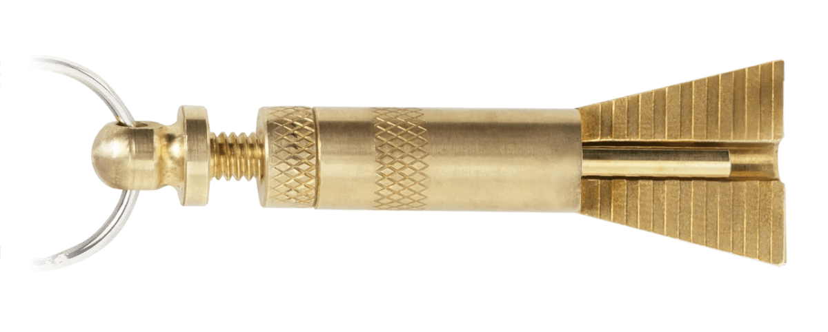 The CK Worldwide Tungsten Stick-Out Gauge (Tg1) is a brass keychain shaped like a dart, with a textured grip and tail fins. Inspired by TIG welding tools, it features a key ring at the tip, attached via a small threaded screw. Plain white background.