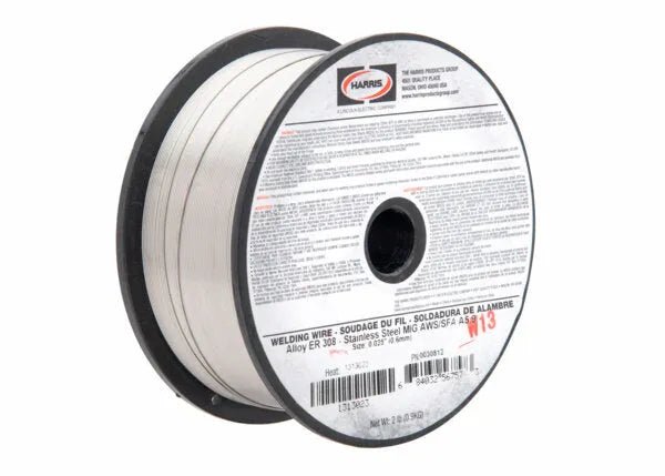 A spool of Harris 308 Stainless Steel MIG GMAW Welding Wire - 0030812 has black rims, metallic wire, and a label with AWS A5.9 info, safety warnings, and product details, marked “113” in red and labeled “Alloy ER 308.”.