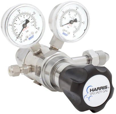 The Harris 742-250-580-E regulator is a high-purity, two-stage model for Argon, Helium, Neon, or Nitrogen. It features dual clear gauges with black/red markings, several fittings, and a large black knob labeled HARRIS SPECIALTY GAS.