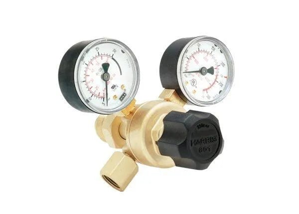 The Harris 3001299 - 601-60CD-320 Single Stage Flowgauge Regulator features a brass body, dual black-rimmed gauges with clear dials, and a large black adjustment knob in a compact design. Comes boxed. Background is white.