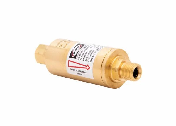 A brass-colored cylindrical flashback arrestor or regulator-type flashguard with a threaded end and a warning label, featuring a large red arrow and text indicating the fuel gas flow direction. The label states Made in Germany.