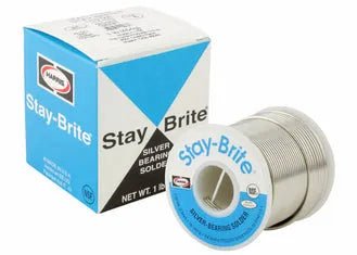 A spool of Harris SBRC65 Stay Brite Lead-Free Rosin Core Solder (1/8 in, 25 lb) sits before its blue and white box packaging, featuring the Harris logo and product name. The metallic solder wire is neatly wound around the spool.