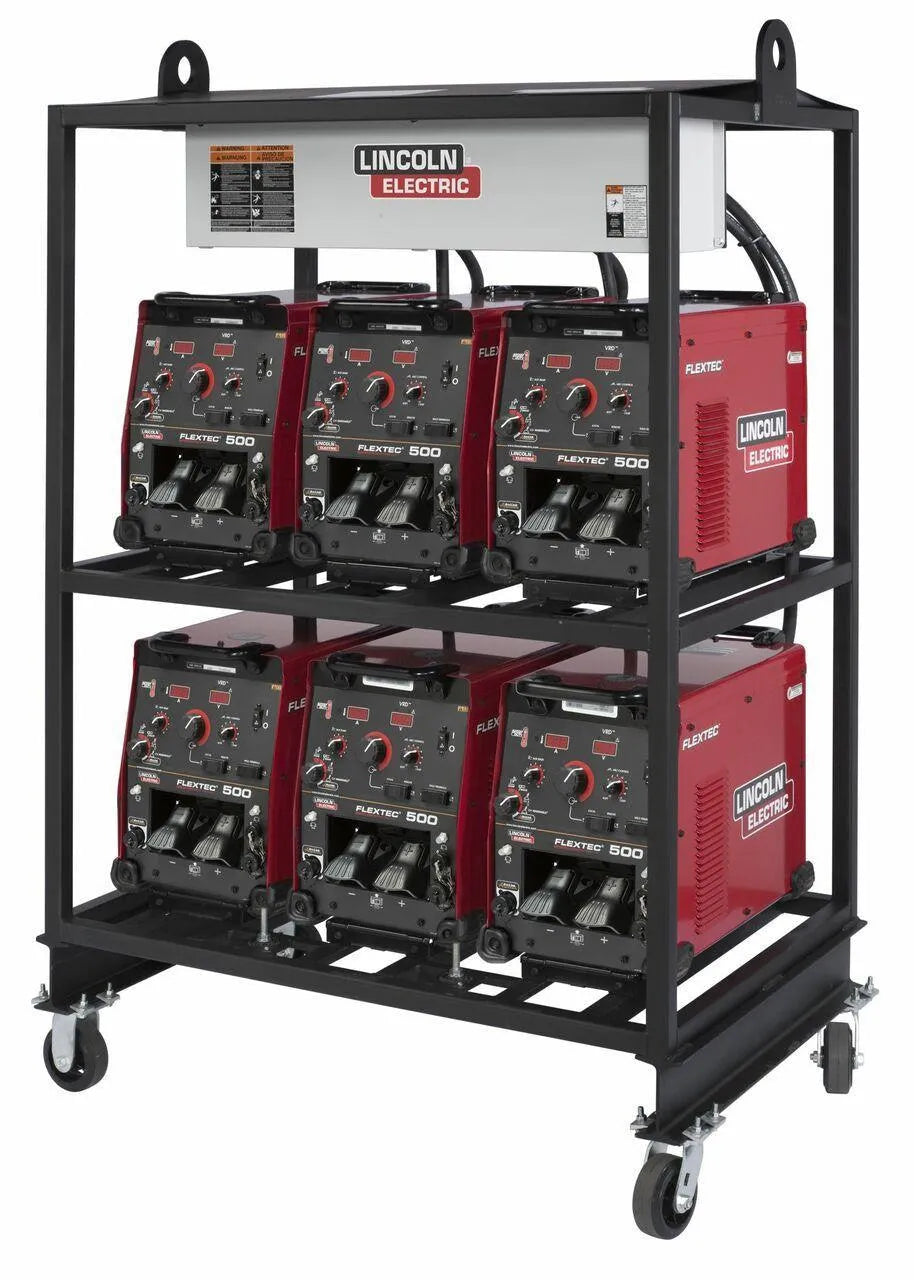 A metal cart on wheels holds six Lincoln 6-PACK RACK FLEXTEC 500 MULTI-PROCESS WELDER K4099-1 units in two rows of three, featuring control dials and digital displays. A white Lincoln Electric box is mounted on top.