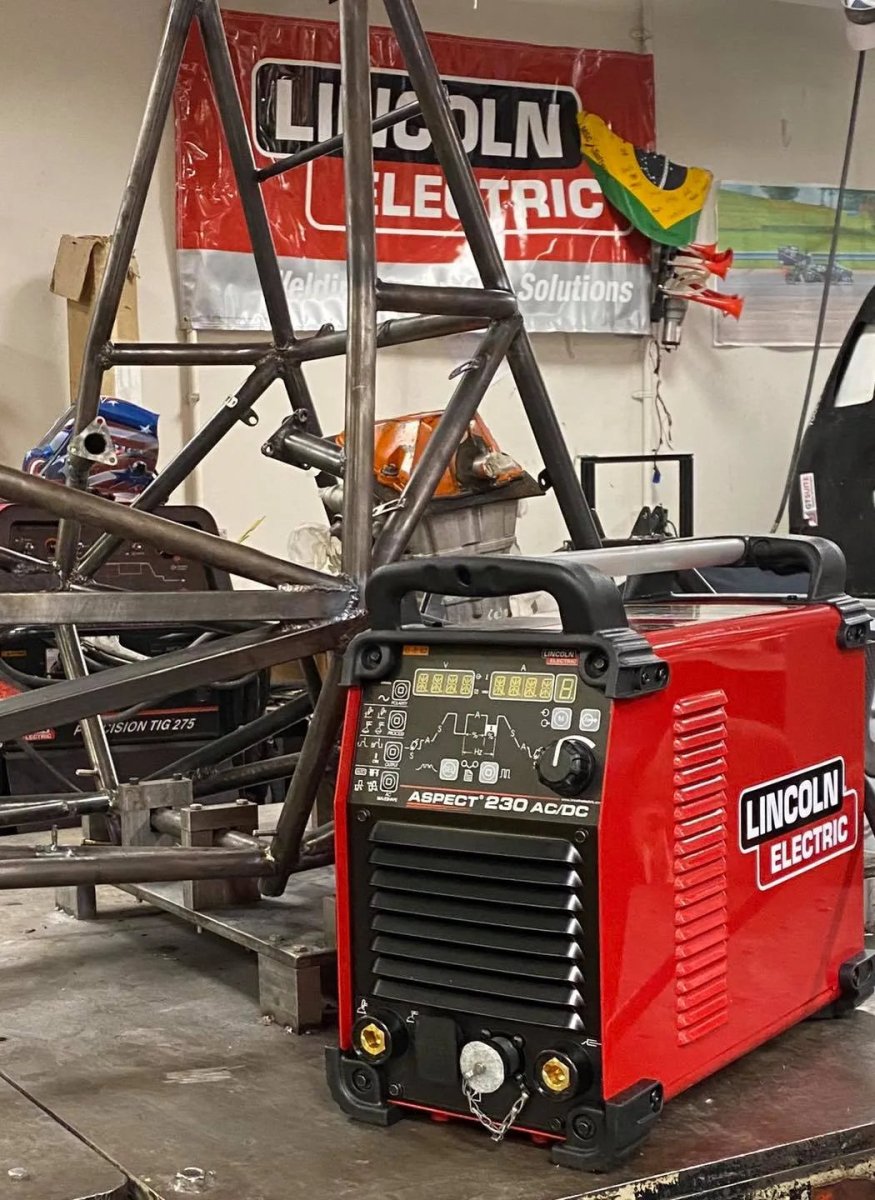 Lincoln Aspect 230 AC/DC TIG Welder U4340-1 on workbench with steel frame, Lincoln Electric banner, WeldingMart welding tools nearby.