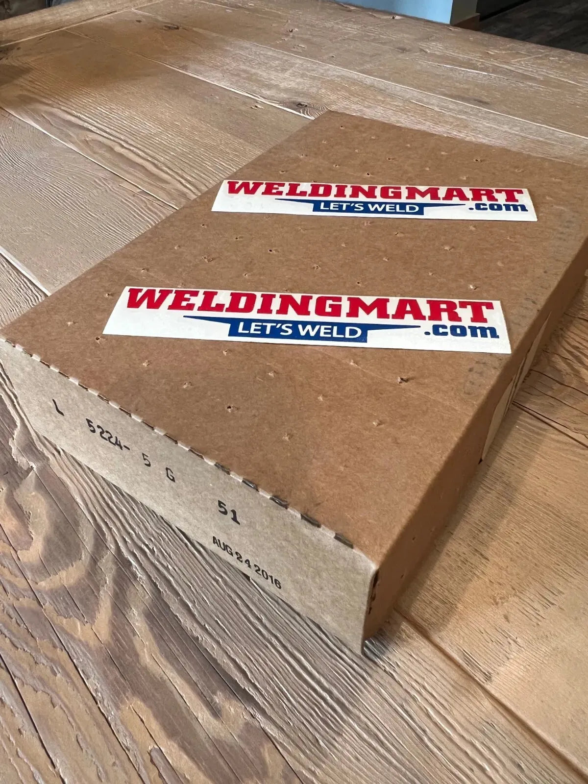 WeldingMart.com box with Lets Weld stickers, Lincoln OEM CONTROL PC BOARD L5224-5, codes, and date on wooden table.
