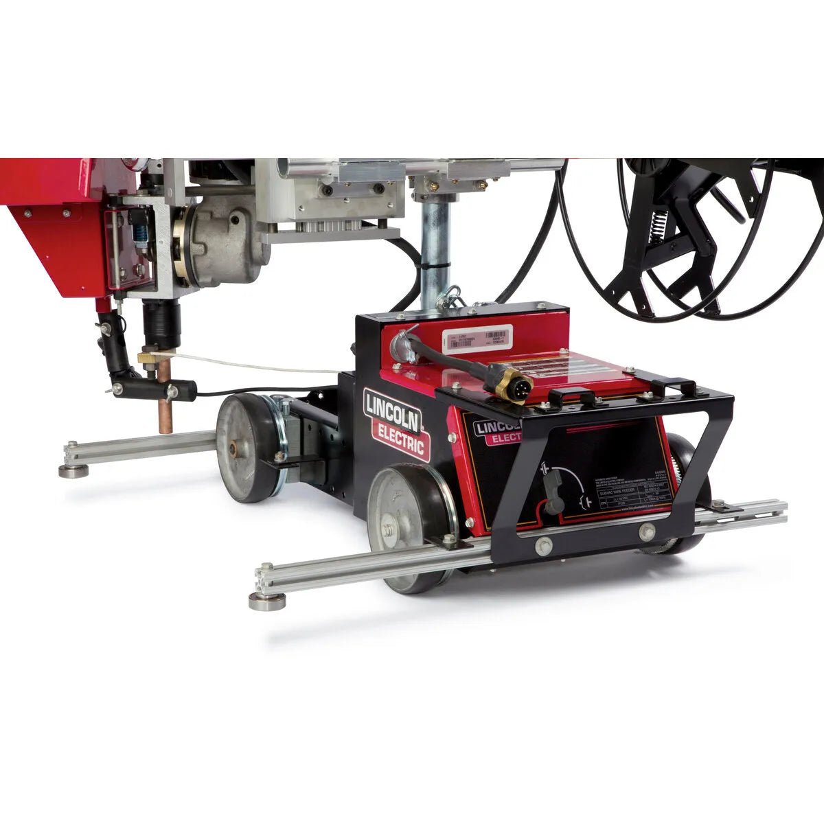 A close-up of the Lincoln Cruiser Submerged Arc Welding Tractor K3048-2 shows its red and black body on wheels, set on metal rails, featuring a control panel, welding gun holder, and mounted wires for automated submerged arc welding.