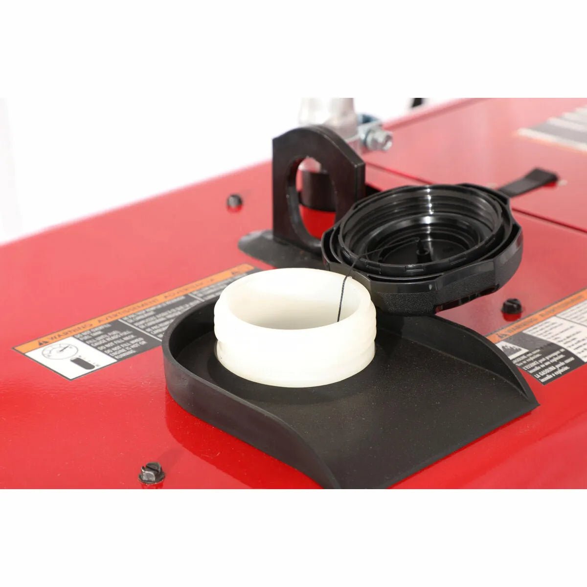 Close-up of a red Lincoln Eagle 10,000 Plus Engine Driven Welder - K2343-4 fuel tank with black cap removed, showing the white plastic fuel opening, metal dipstick, and partial instructional and warning labels.