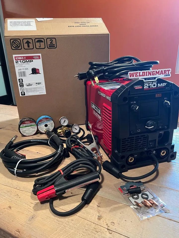Lincoln Electric Power Mig 210 MP Multi-Process Welder with cables, wire spools, tools, and box on wood floor at WeldingMart.