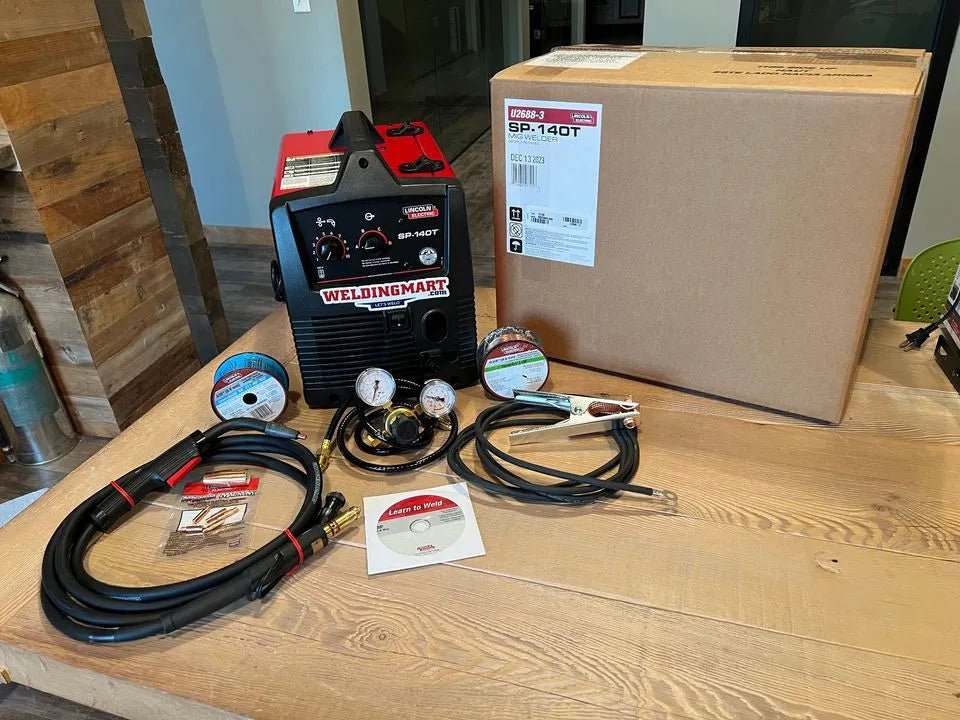 Lincoln Electric SP 140T MIG Welder kit with cables, gauges, clamps, wire spools & box on table—pro welding equipment.