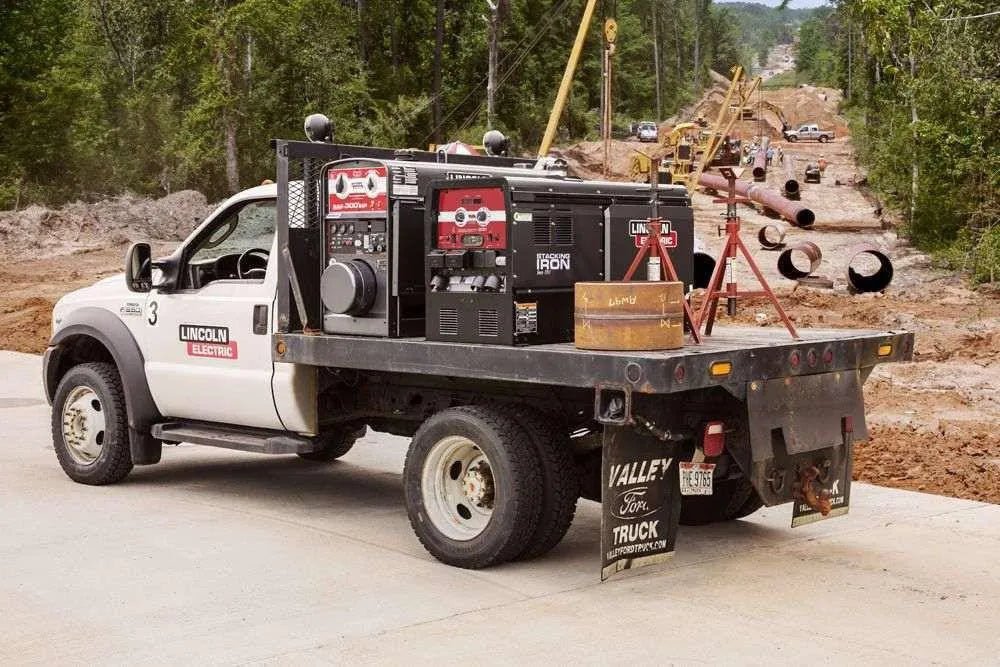 WeldingMart pipeline work truck with Lincoln Factory Demo Cross Country 300 (Kubota) welder at construction site laying large pipes.