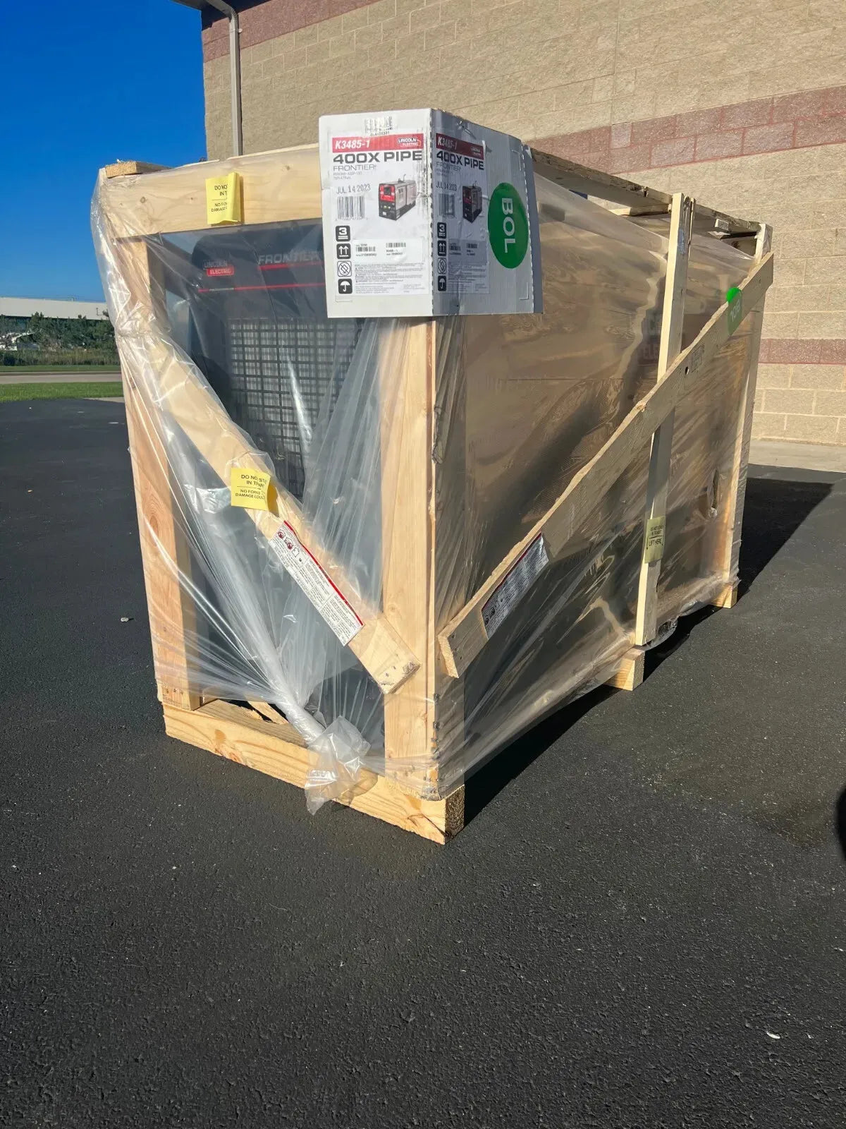 A large industrial air conditioning unit in a wooden crate is wrapped in clear plastic. A box on top labeled “400X PIPE” refers to the Lincoln Frontier 400X Pipe Engine Driven Welder Perkins - K3485-1, designed for pipeline welding jobs.
