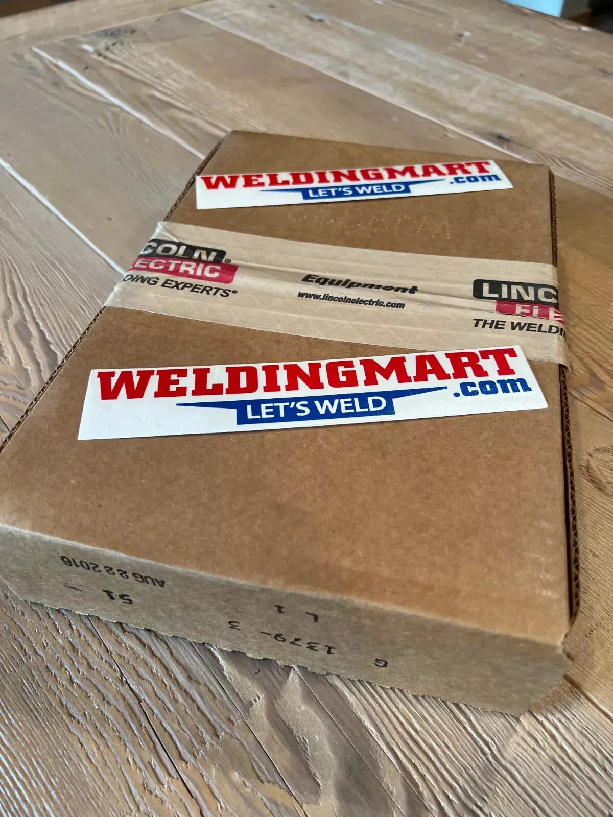 Lincoln OEM Logic PC Board Assembly G1379-3 from WeldingMart, in a branded box with stickers and tape on a wooden surface.