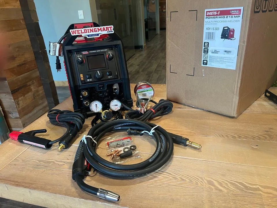 Lincoln Power MIG 215 MPi Welder U4876-1 with cables, clamps & accessories on table by box—WeldingMart welding equipment.