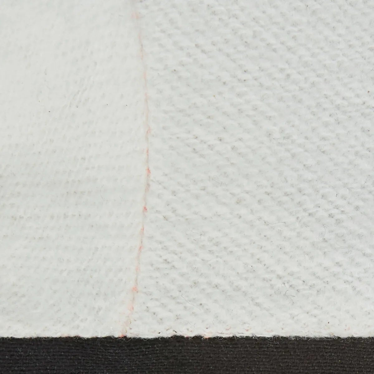 Close-up of Lincoln Premium 7 Series Elkskin Stick/MIG Welding Gloves (M K4787-M) featuring textured white elkskin, a subtle vertical red seam left of center, and a solid black band along the bottom edge for bold contrast.