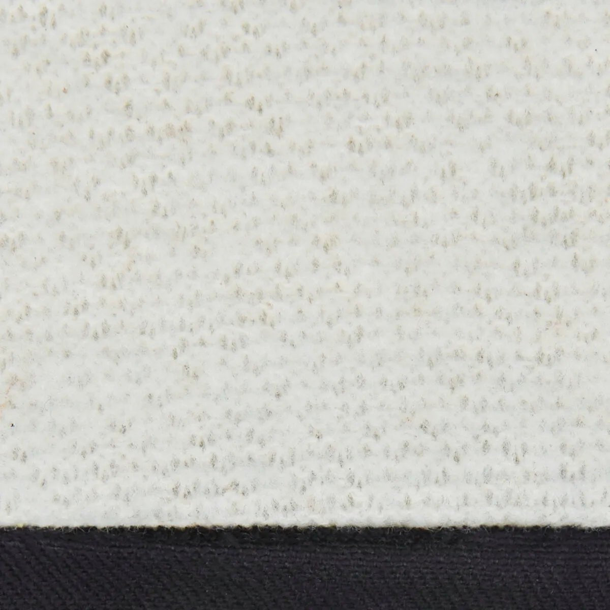 Close-up of a textured white fabric with small, even bumps and a black strip at the bottom—similar to the durable materials in Lincoln Premium 8 Series Elkskin Stick/MIG Welding Gloves K4788-M for enhanced heat protection.