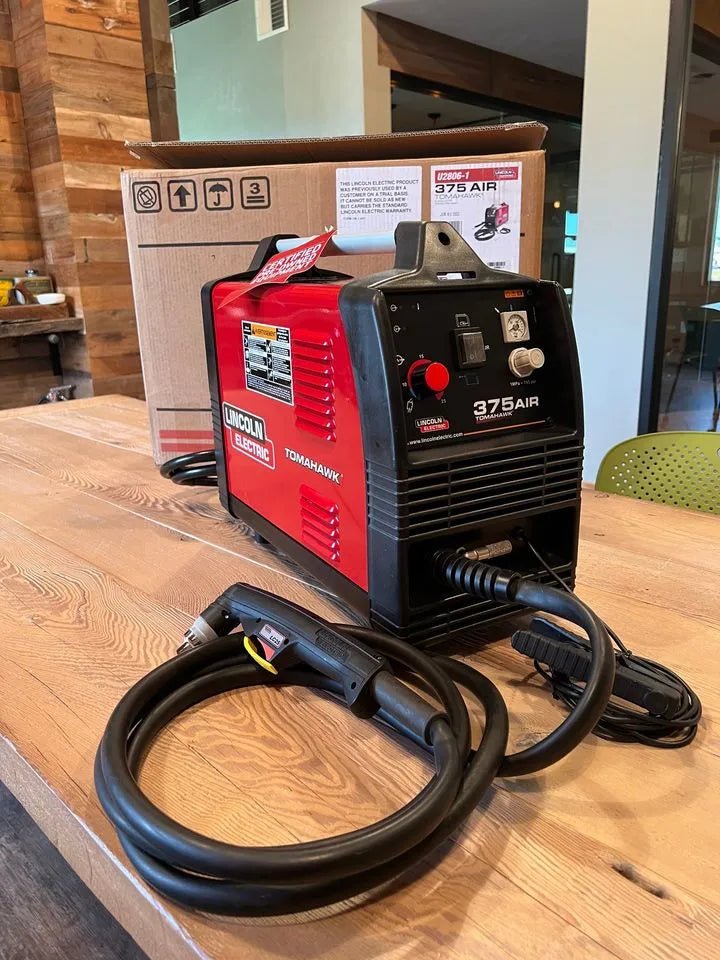 Lincoln Tomahawk 375 AIR Plasma Cutter (U2806-1) with cable and torch on table, WeldingMart welding equipment in background.