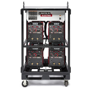 A tall black metal cart equipped with the Lincoln Caster Kit K2665-1 holds four Lincoln Electric welding machines (two per shelf) with a control unit on top; red and black designs with knobs, displays, and thick cables are visible.