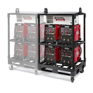 Two metal inverter racks, each equipped with a Lincoln Caster Kit K2665-1 for mobility, hold several red Lincoln Electric welding machines. The right rack shows four welders clearly; the left is faded with only faint outlines visible.