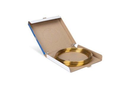A coil of Harris 30650 Safety-Silv 30 Silver Brazing Alloy, 1/8 in (3.2 mm), is arranged in a flat spiral inside an open plain brown box with white flaps, with the shiny alloy wire resting on a white background.