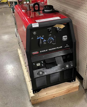 A Lincoln Eagle 10,000 Plus Engine Drive Factory Demo Welder (U2343-4) in red and black sits on a wooden pallet in-store, control panels and labels visible. A $4999.00 price tag is attached to the top.