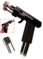 A black stud welding gun with a labeled handle, metal attachment at the tip, and two cables extending from the bottom; includes an inset showing the industrial welding gun held in a hand and a separate metal component.