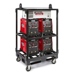 A black metal cart with handles and loops, equipped with a Lincoln Caster Kit K2665-1, holds four red and black Lincoln Electric welders on two shelves and a white unit on top; each welder displays various dials and ports.