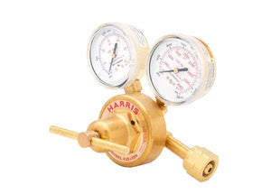 A brass single stage regulator with two analog gauges and a control knob. The gauges display pressure readings, and the device is labeled HARRIS. This industrial gas regulator is used for controlling gas flow.