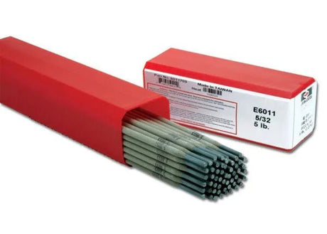 A partially open red box reveals Harris 6011 Stick SMAW Electrode 5/32 rods inside. An identical closed box marked 6011705 sits nearby—ideal all-position steel electrodes—both resting on a plain white background.
