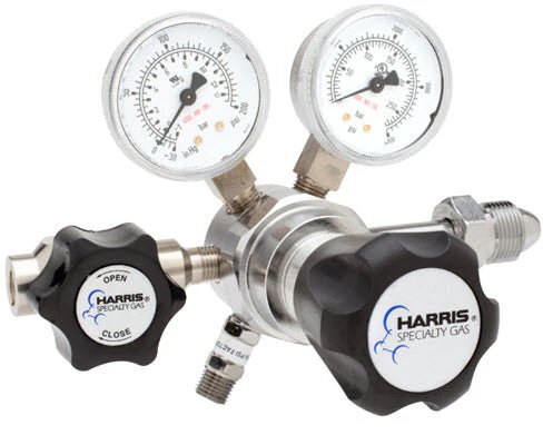 The Harris Two Stage Ultra High Purity Brass Barstock Regulator Model 721C-050-580-B features dual pressure gauges (psi/kPa), black “Open” and “Close” knobs, and multiple side connectors. The regulator is labeled "Harris Specialty Gas.
