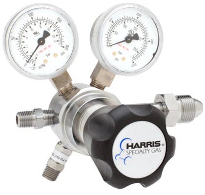 The Harris Two Stage Ultra High Purity Brass Barstock Regulator Model 721C-125-580-C features two pressure gauges, a large black adjustment knob with blue Harris branding, multiple threaded connectors, and a stainless steel diaphragm.