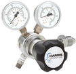 The Harris Two Stage Ultra High Purity Brass Barstock Regulator Model 721C-050-580-D features dual pressure gauges, a large black "HARRIS SPECIALTY GAS" control knob, several fittings, and a stainless steel diaphragm for precise control.