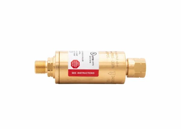 A brass inline water flow sensor with threaded connectors on both ends, featuring a white and red label displaying instructions and specifications, similar in form to a regulator-type flashback arrestor, isolated on a white background.