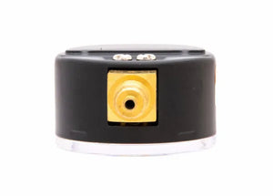 Close-up of a black and gold regulator pressure gauge featuring a central circular port and two small metal connectors on top, set against a white background.