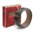 A Lincoln 1/16 METALSHIELD MC-6 60# COIL ED030577 stands upright beside a red and beige Lincoln Electric box, featuring bold designs and prominent branding. The metallic wire is neatly wound inside the coil.