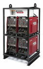 Four red Lincoln Electric Flextec 650 welding machines are stacked in two rows within a black metal rack, creating a robust multi-operator welder system. The equipment features various control knobs and connection ports on the front panels.