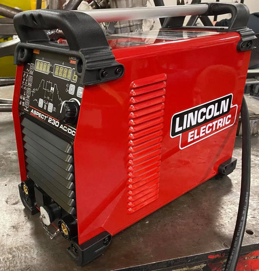 Lincoln Aspect 230 AC/DC TIG Welder (U4340-1), red, with control knobs, digital displays, welding ports; on metal surface.