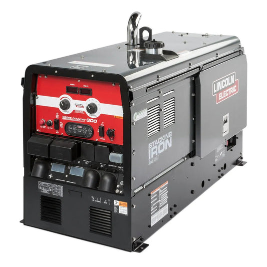 The Lincoln Cross Country 300 Kubota Engine Driven Welder (K4166-1) features a black and silver body, chrome exhaust, and red/black control panel with multiple dials and meters—ideal for pipeline welding. Labeled STACKING IRON.