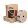 A spool of SuperGlide S6 MIG wire sits next to two cardboard boxes labeled Lincoln Electric, featuring the brand logo and a graphic design—ideal for mild steel welding projects.