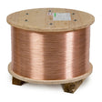 A large wooden spool holds a long length of shiny Lincoln Electric SuperArc L-56 MIG welding wire tightly wound around it. The spool has a flat top and bottom with visible metal bolts and labels attached to the top surface.
