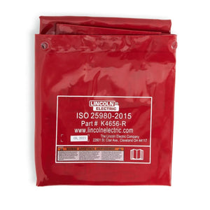 A folded red Lincoln Flame Retardant Vinyl Welding Screen/Curtain 6 x 6 ft. (K4656-R) displays white text: LINCOLN ELECTRIC, ISO 25980-2015, part number, website, plus front-facing details, warnings, and company address.