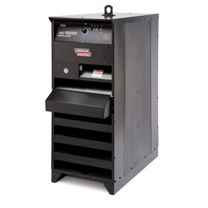 A large black Lincoln Idealarc AC1200 Subarc Welder - K3140-2, featuring a control panel with dials, vents, and an open shelf below the main console, stands against a plain white background.