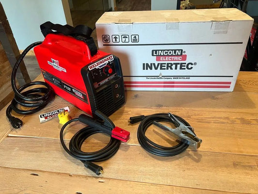 Lincoln Invertec V155-S Stick Welder (K2605-1) with cables, welding accessories, and Lincoln Electric sticker on a wooden table.
